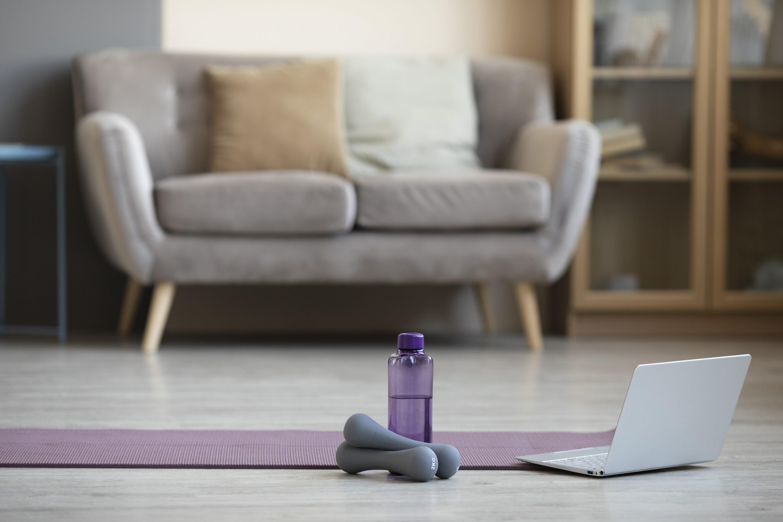 Dumbbells and mat on a living room floor for home fitness routines.